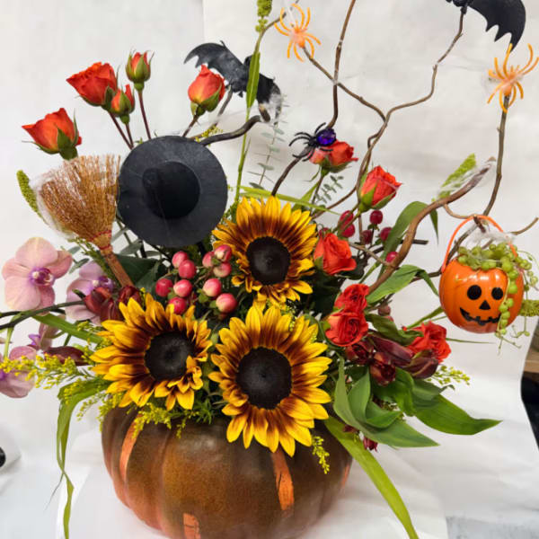 Halloween floral arrangement in a pumpkin vase with sunflowers and roses