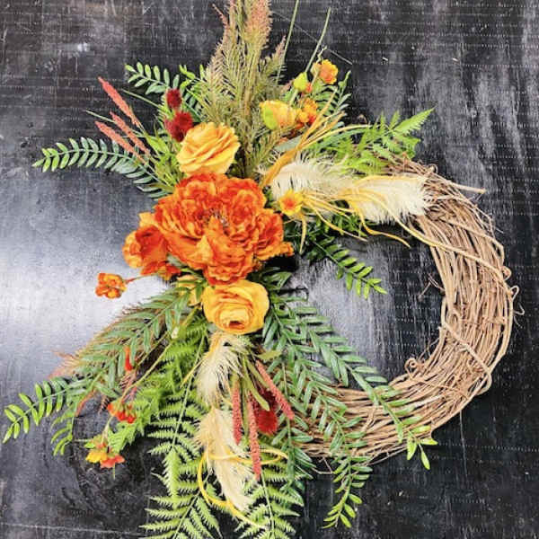 Orange floral wreath with a grapevine base and mixed greenery