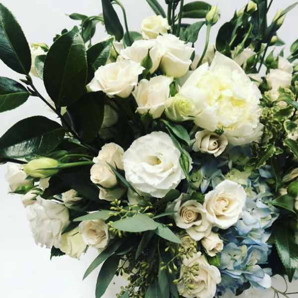 White roses and pale blooms arranged with dark green foliage