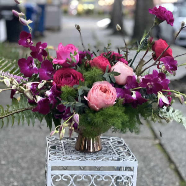 Pink and purple floral arrangement in a small copper vase