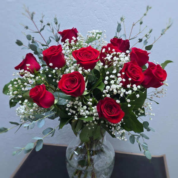 Red roses with baby's breath in a clear glass vase