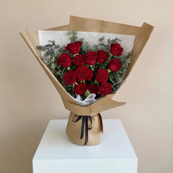 Bouquet of red roses wrapped in brown paper with a black ribbon