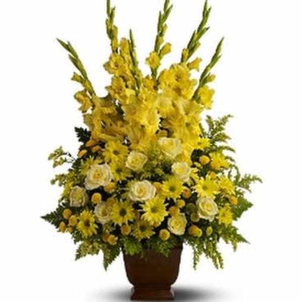 Tall yellow floral arrangement in a brown urn vase