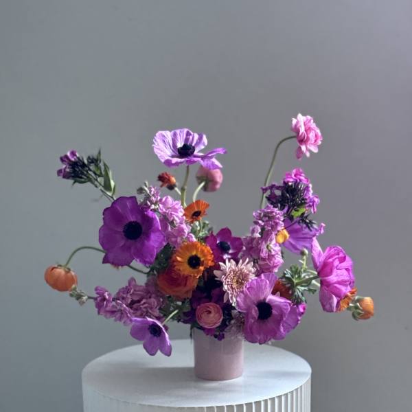 A small vase arrangement of purple, pink, and orange flowers