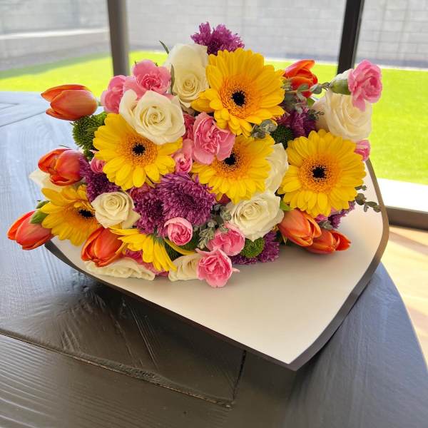 Bouquet of yellow gerbera daisies, white roses, pink carnations, and orange tulips