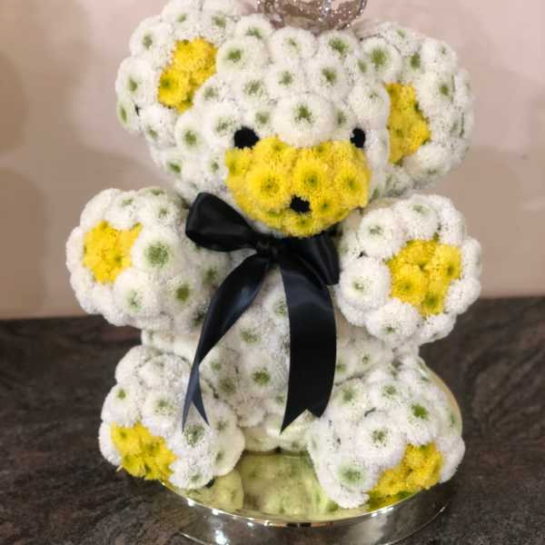 Teddy bear made of white and yellow flowers with a black ribbon