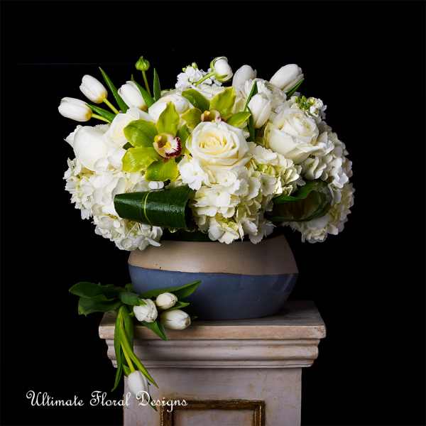 White roses and tulips arranged in a low vase with green orchids