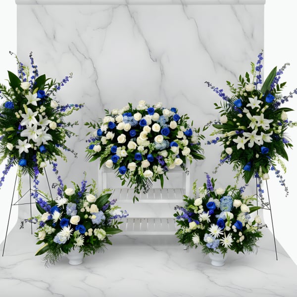 Blue and white floral funeral display with standing sprays and vase arrangements