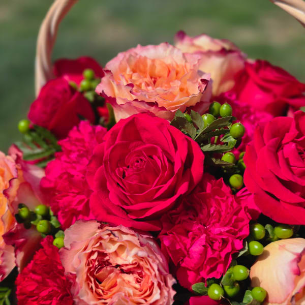 Bouquet of pink and peach roses with carnations in a basket