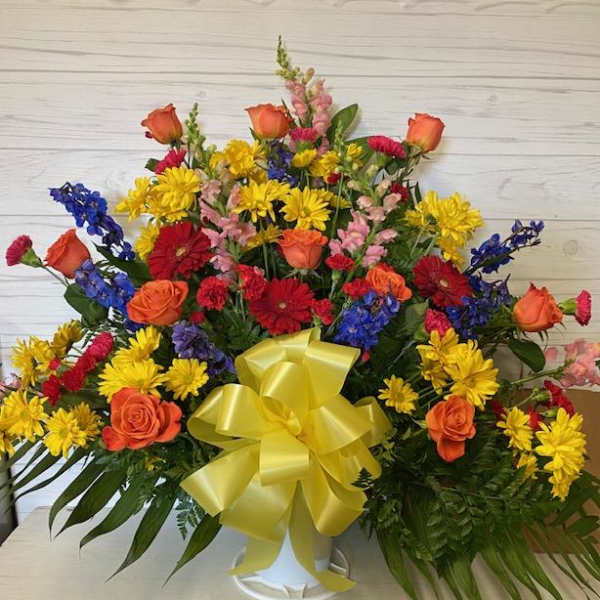 Colorful mixed flower arrangement in a white vase with a yellow bow
