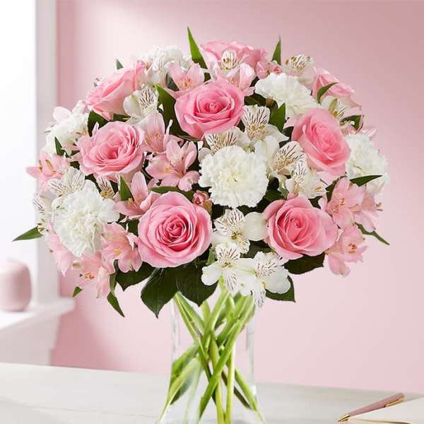 Pink roses and white flowers arranged in a clear glass vase