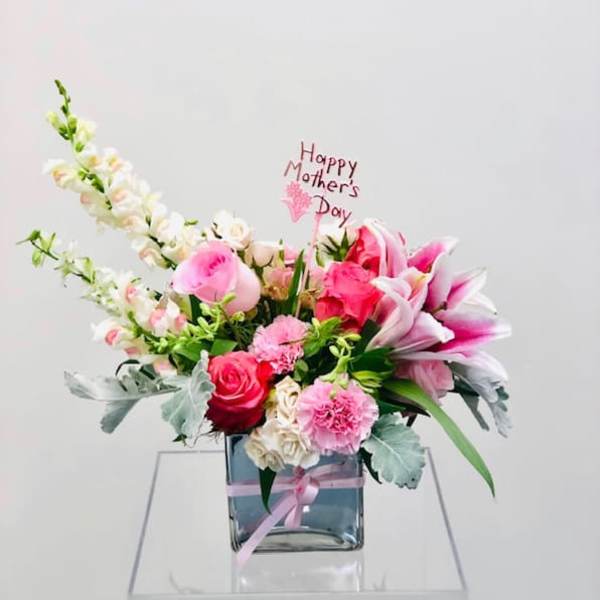 Pink and white floral arrangement in a glass vase with a Mother's Day sign