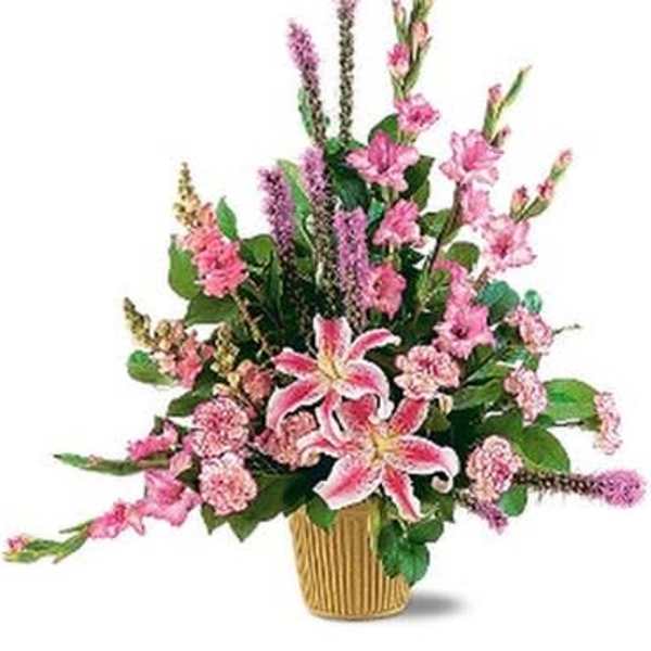 Pink lilies and mixed flowers in a ribbed gold vase