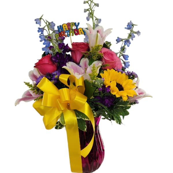 Mixed bouquet with roses, lilies, sunflowers, and a birthday pick in a vase