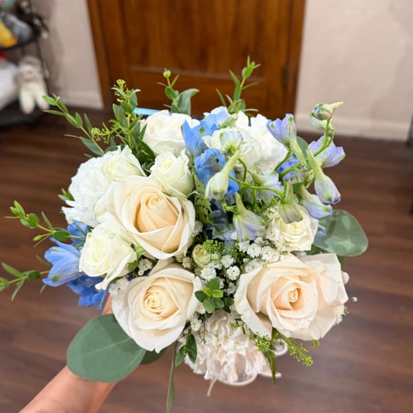 Bouquet of cream roses and blue flowers with greenery