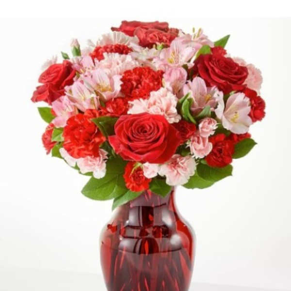 Red and pink flower bouquet in a red glass vase