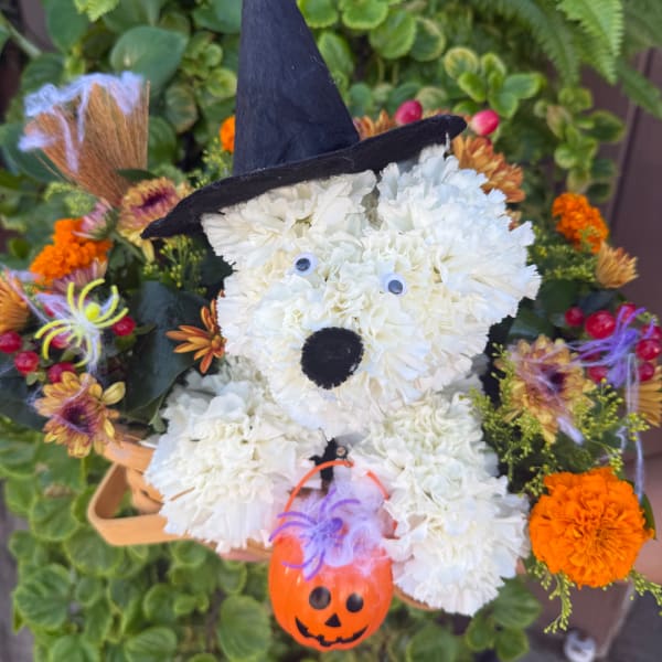 White floral dog arrangement with a black witch hat and pumpkin ornament