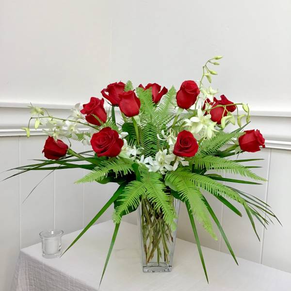 Red roses and white orchids in a clear glass vase