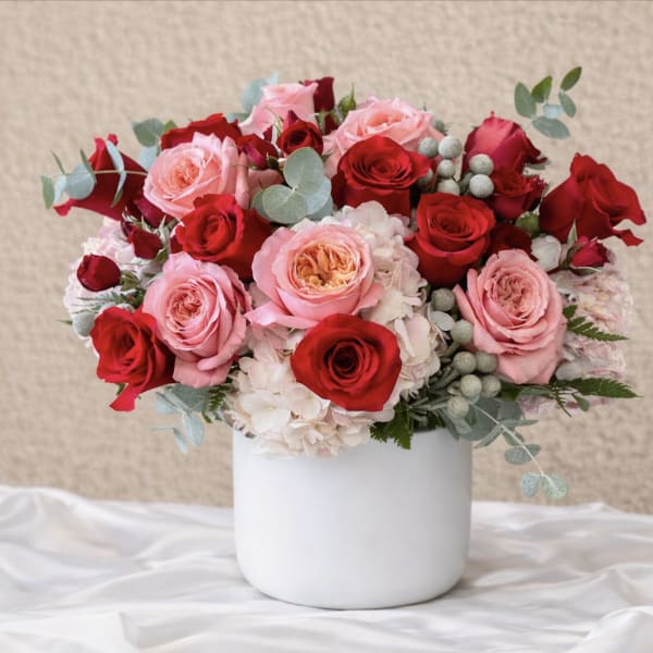 Pink and red roses arranged in a white vase