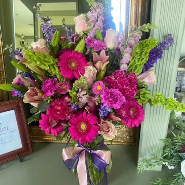 Bright mixed bouquet with pink gerberas, roses, and purple blooms in a vase