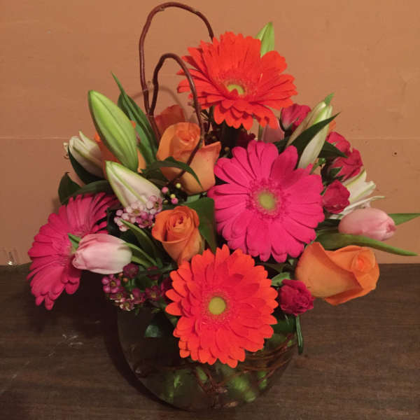 Bright mixed bouquet in a glass vase with gerbera daisies, roses, and lilies