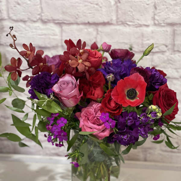 Mixed bouquet of red, pink, and purple flowers in a glass vase