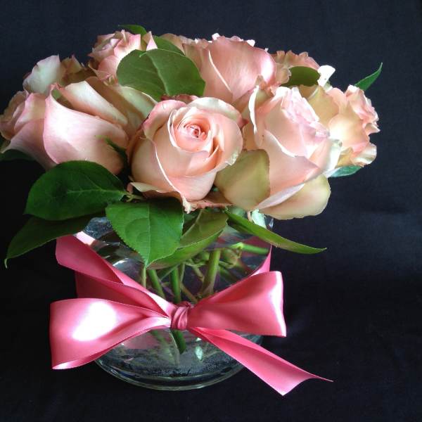 Pink roses in a clear glass vase tied with a pink ribbon