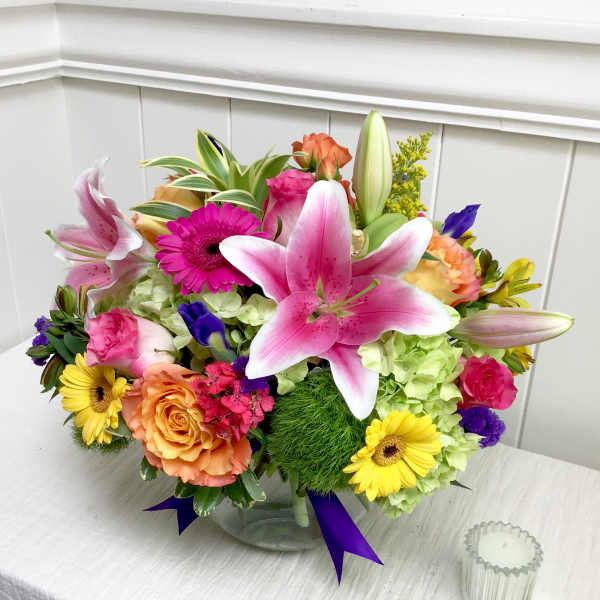 Mixed bouquet in a clear glass vase with pink lilies, roses, and gerbera daisies
