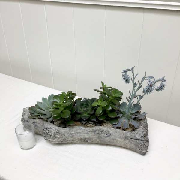 Succulent arrangement in a rustic wood planter with a small glass votive
