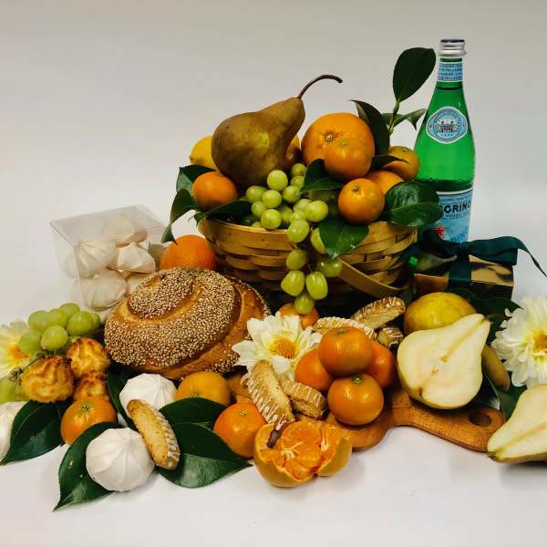 Fruit and bread gift basket with flowers and a green bottle