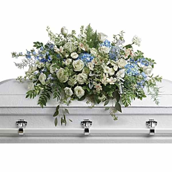 White and blue floral casket spray on a white coffin