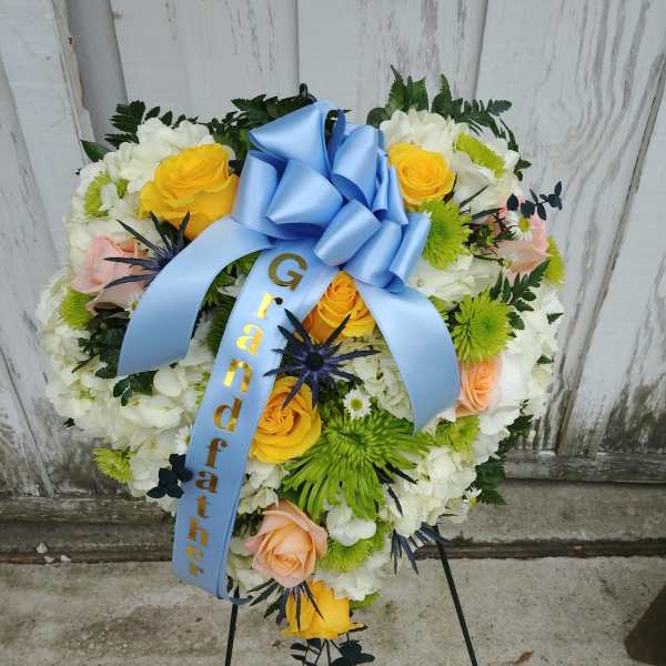 Heart-shaped floral wreath with a blue ribbon and stand