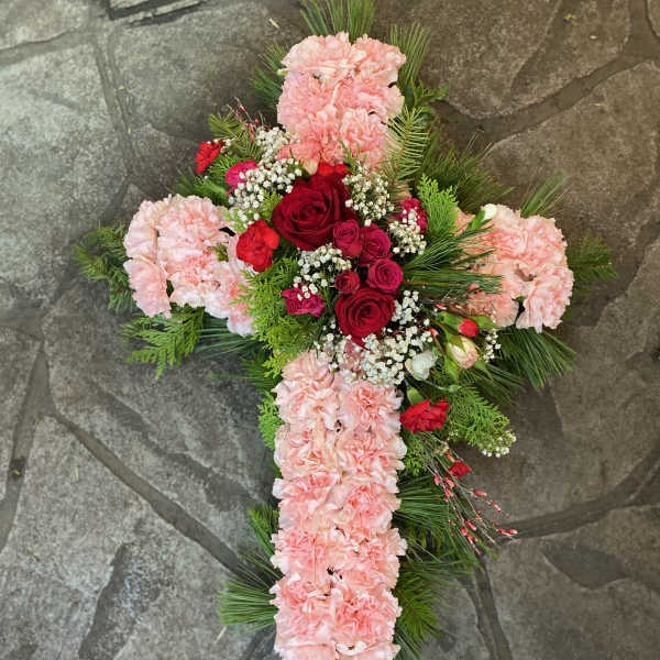 Cross-shaped floral arrangement with pink carnations and red roses