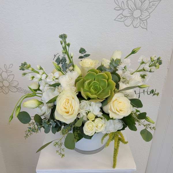 White rose arrangement with a green succulent in a white vase
