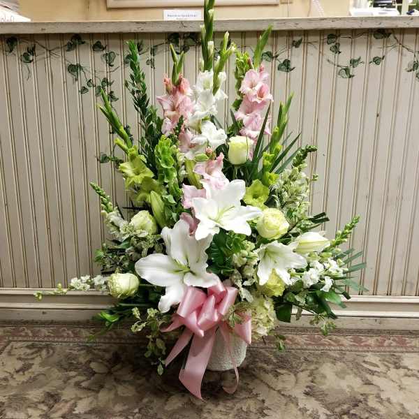 Tall floral arrangement with white lilies and pink gladiolus in a vase