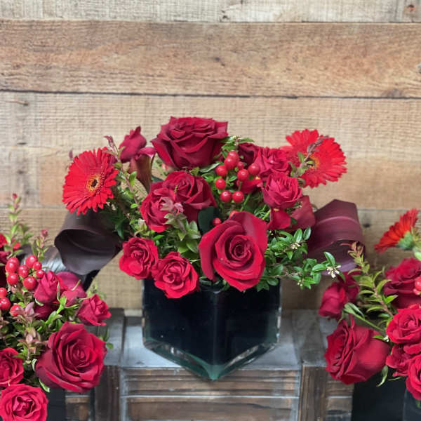 Red rose arrangement with gerbera daisies in a black vase