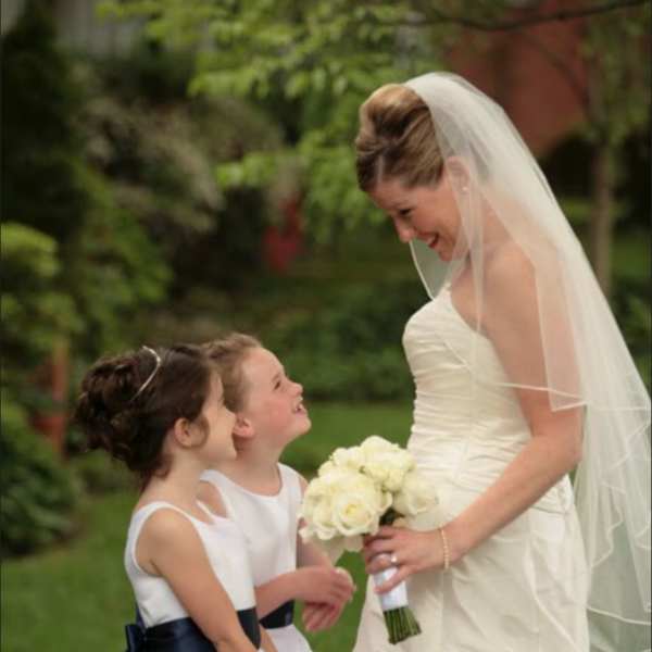 Bride in a white dress holding a white bouquet beside two flower girls