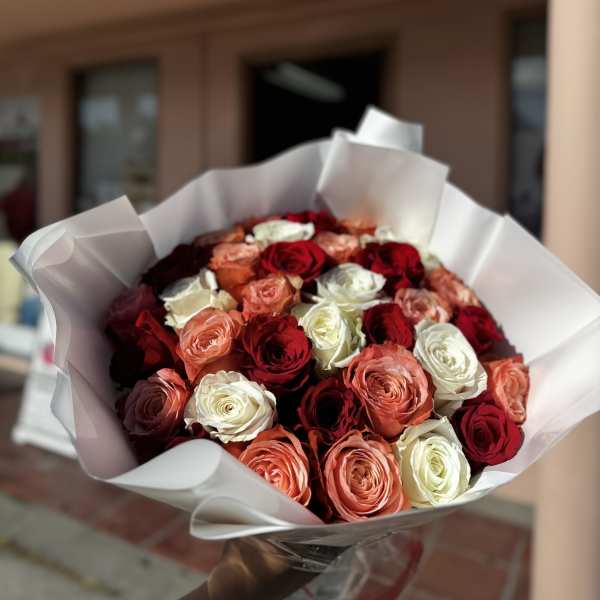Bouquet of red, white, and peach roses wrapped in white paper