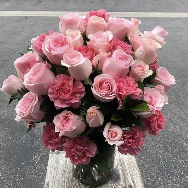 Pink roses and carnations arranged in a clear glass vase