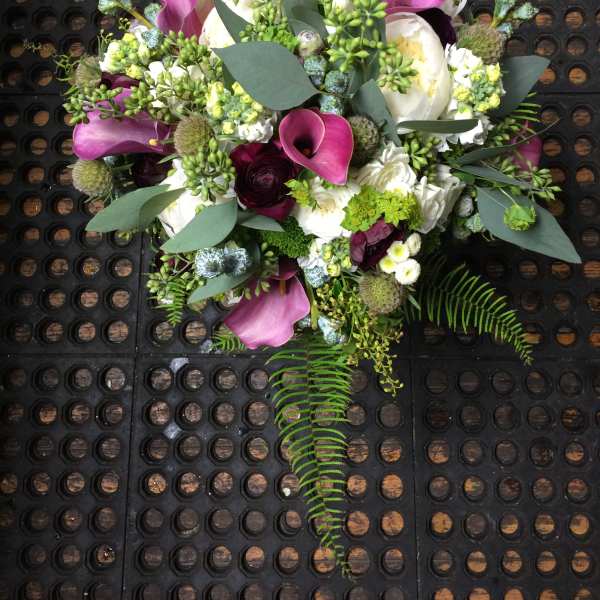 Bouquet of purple calla lilies and white blooms with greenery