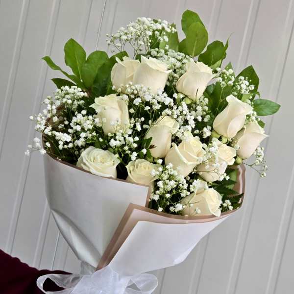 Bouquet of white roses and baby's breath wrapped in white paper