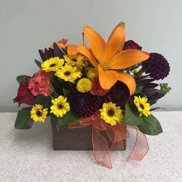 Orange lily and mixed yellow and burgundy flowers in a wooden box