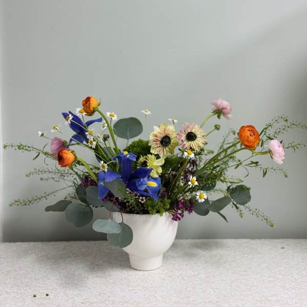 Mixed bouquet in a white vase with blue and orange blooms
