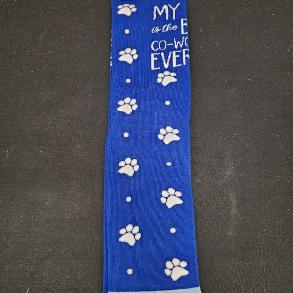 Blue tie with white paw prints and partial text on a dark background