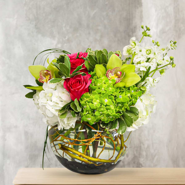 Bouquet of pink roses, green orchids, and white blooms in a glass vase