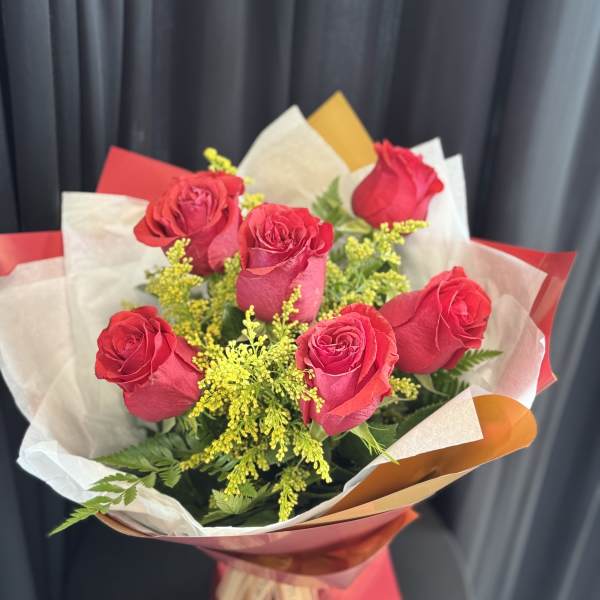 Bouquet of red roses with yellow filler flowers in wrapped paper