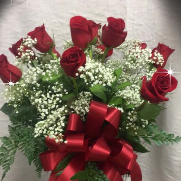 Bouquet of red roses with baby's breath in a glass vase and red ribbon