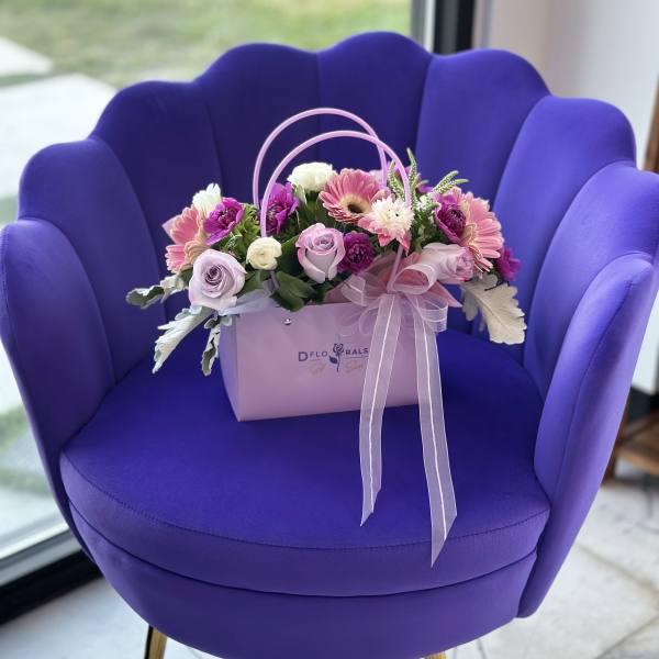 Pink and purple flower arrangement in a lavender gift box with ribbon