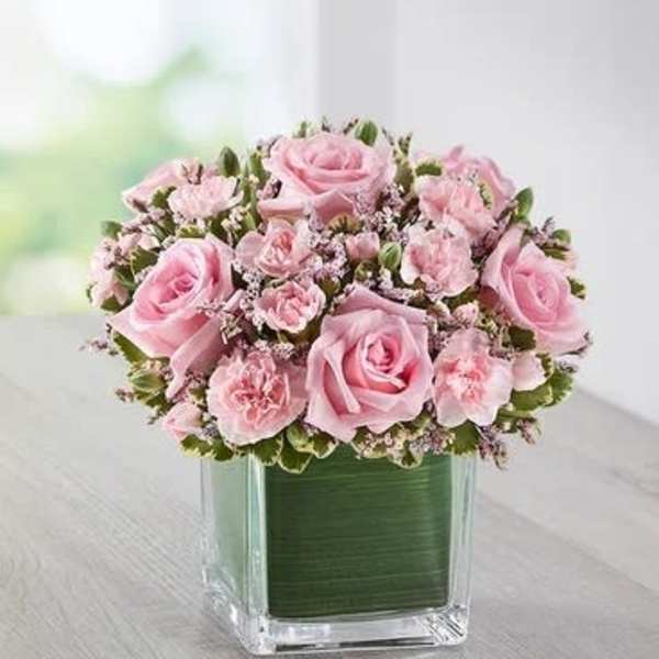 Pink roses and carnations arranged in a square glass vase