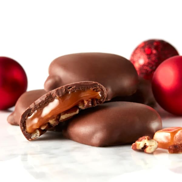 Chocolate-covered candies with caramel and nuts, surrounded by red ornaments
